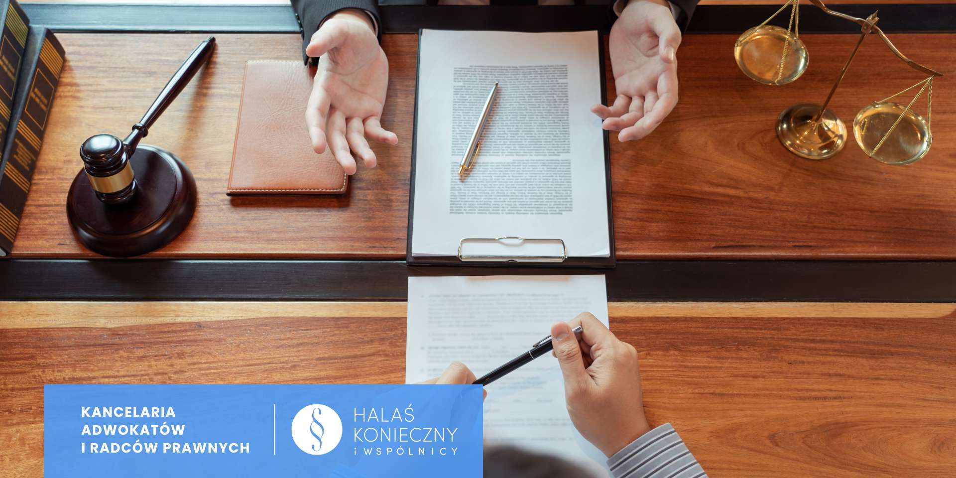 Rzut z góry na biurko w kancelarii, rozmowa z klientem, podpisanie umowy