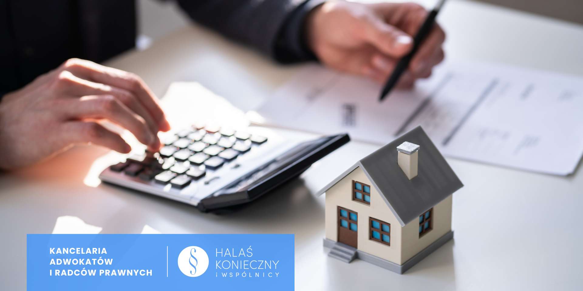 adwokatrodzinny (2) Osoba przy biurku, dokumenty, kalkulator, makieta domku