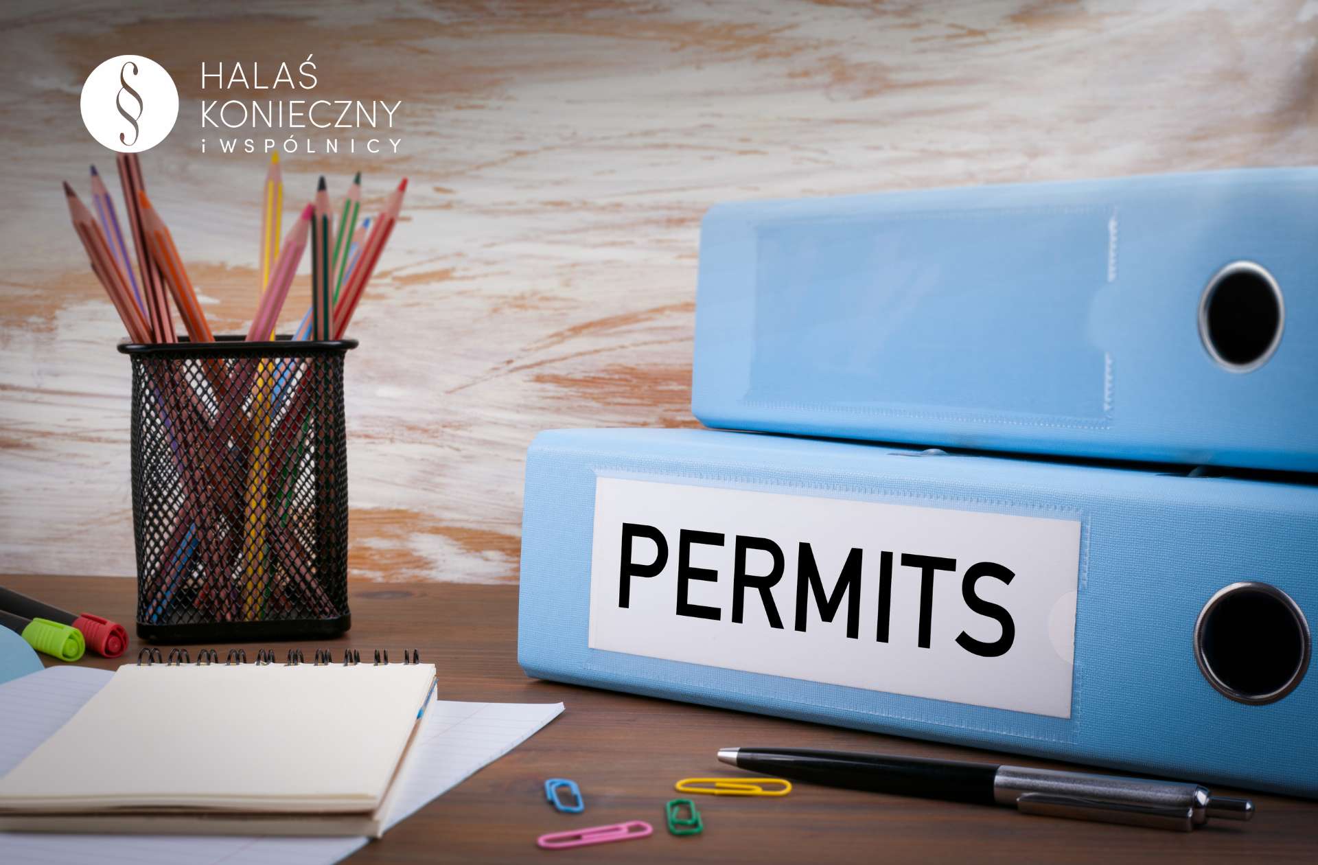 zezwolenienapobyt1 Biurko z przyborami, niebieskie segregatory z napisem "permits"
