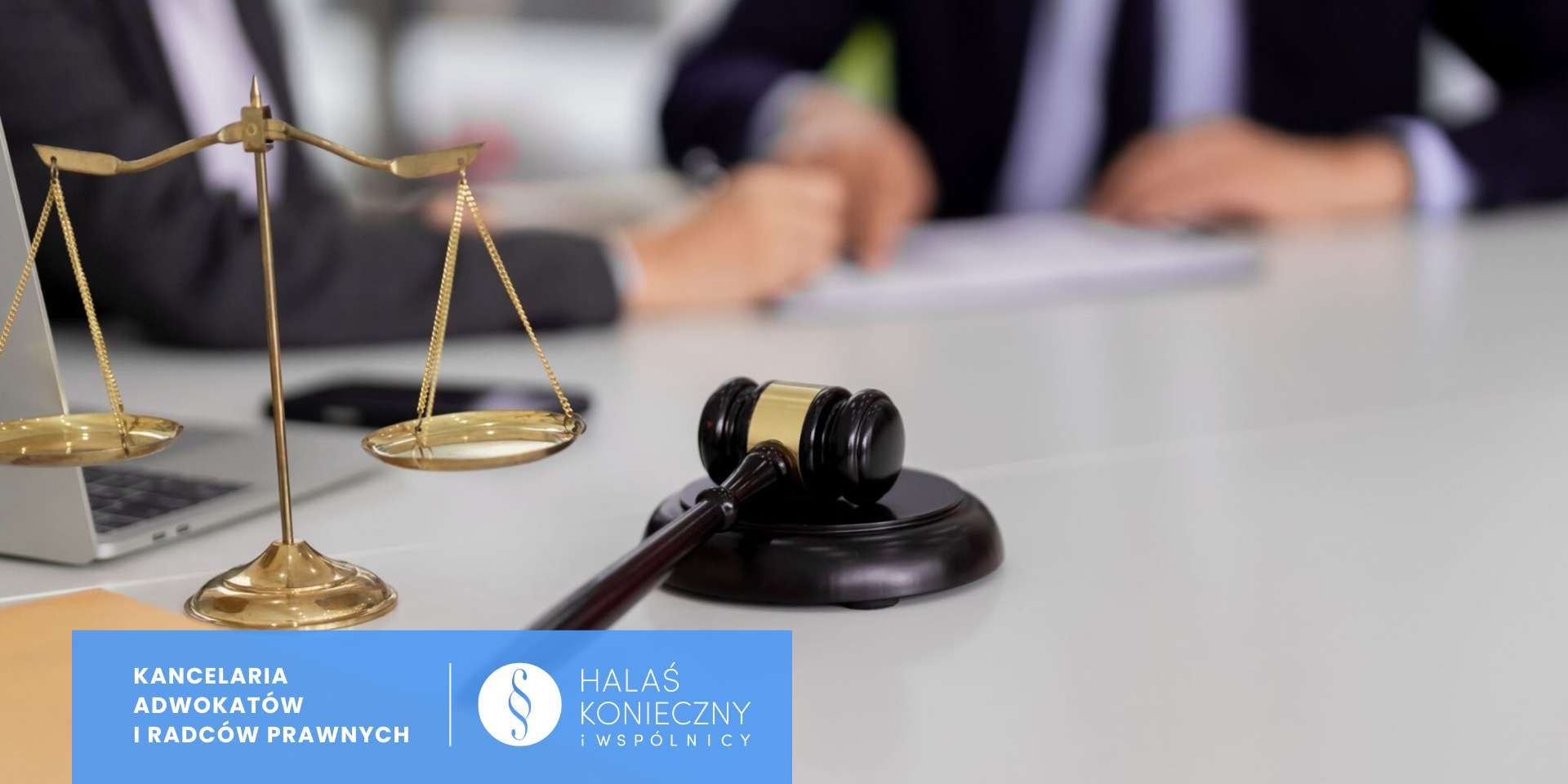 Gold balance scales and a judge's gavel on a desk, with two people signing papers in the blurred background and a blue law-firm banner in the corner.